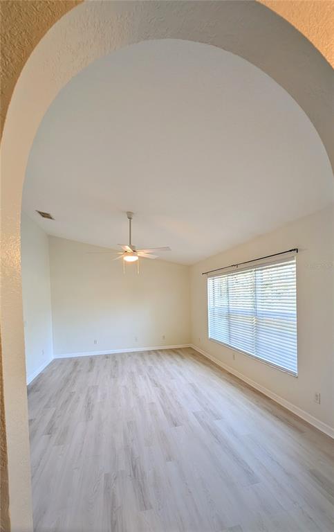 An empty room with light wood-look flooring, a ceiling fan, and an arched entryway — 4023 N EAGLE NEST POINT, CRYSTAL RIVER, FL