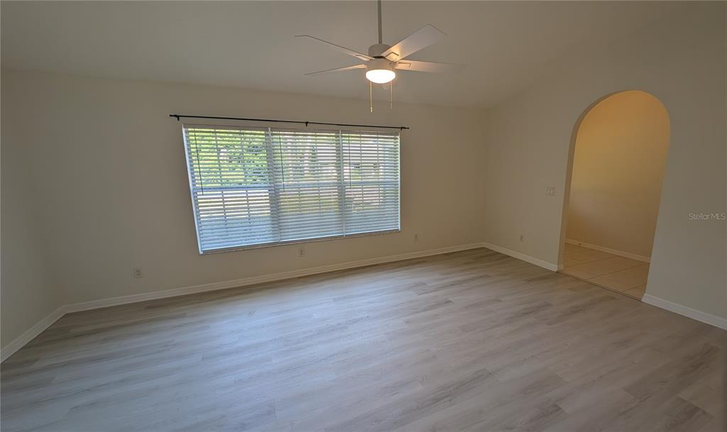 An empty room features light wood-look flooring, white walls, a ceiling fan, and an arched doorway — 4023 N EAGLE NEST POINT, CRYSTAL RIVER, FL