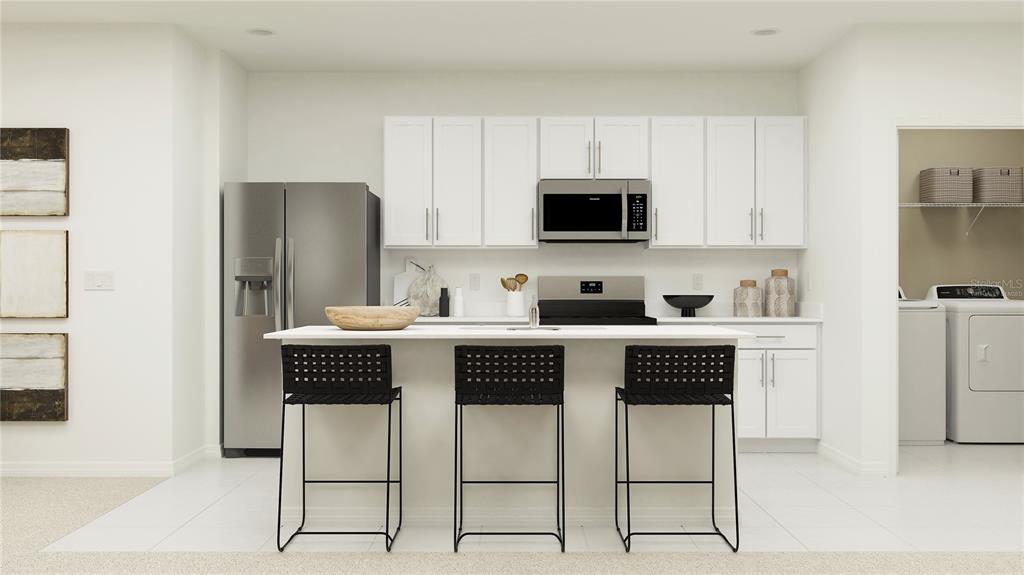 A modern kitchen features white cabinetry, stainless steel appliances, a central island, and three stools — 2439 BLUESTONE ROAD, HAINES CITY, FL