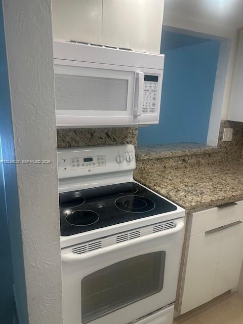 A white electric stove and over-the-range microwave are set against granite countertops in a kitchen — 10395 N Kendall Dr # V4, Miami FL 33176, MIAMI, FL