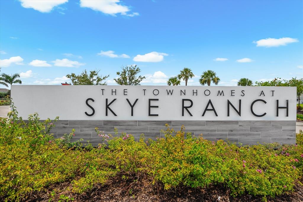 A white monument sign reads The Townhomes at Skye Ranch against a blue sky — 8701 WINTER BREEZE, SARASOTA, FL