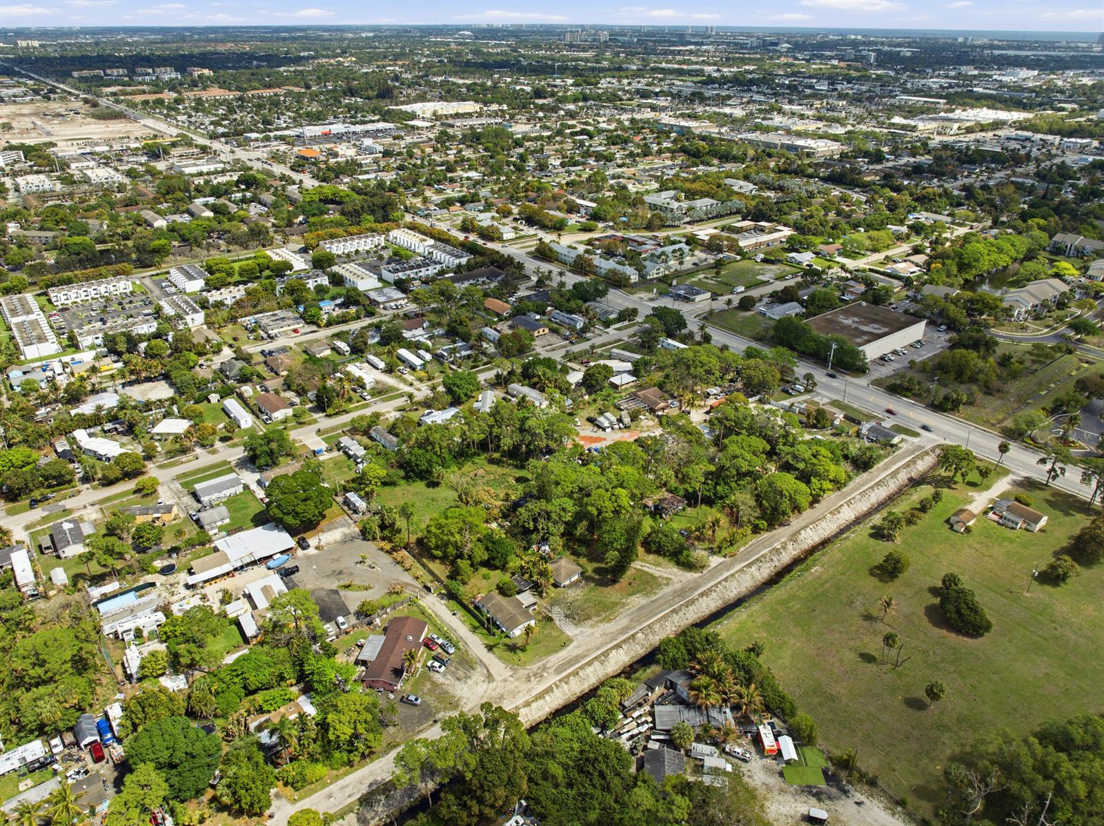 An aerial view shows a residential neighborhood with houses, trees, and a canal — 5133 Pine Grove Drive, West Palm Beach FL 33417, WEST PALM BEACH, FL