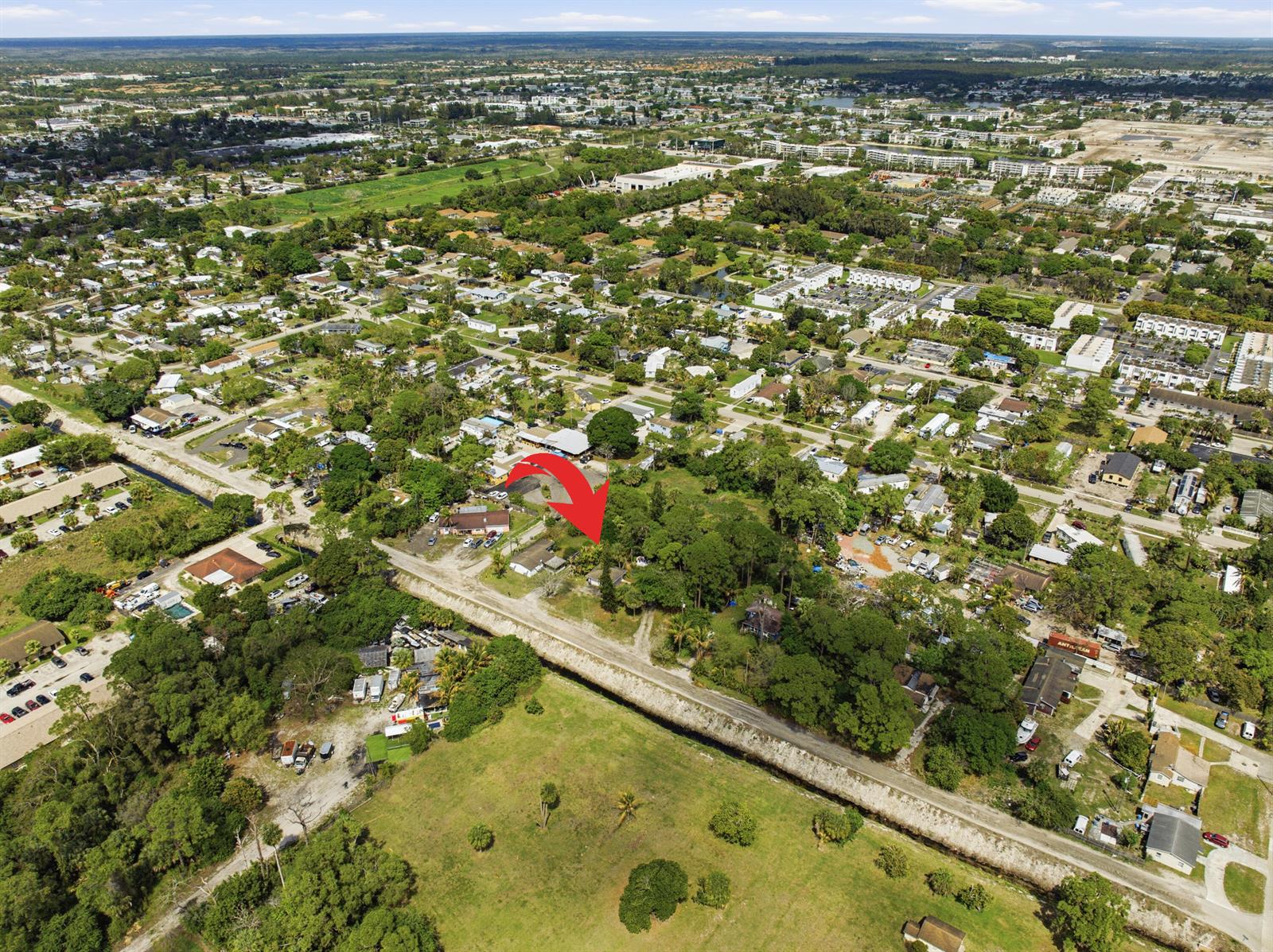 An aerial view shows a residential property marked by a red arrow near a canal — 5133 Pine Grove Drive, West Palm Beach FL 33417, WEST PALM BEACH, FL