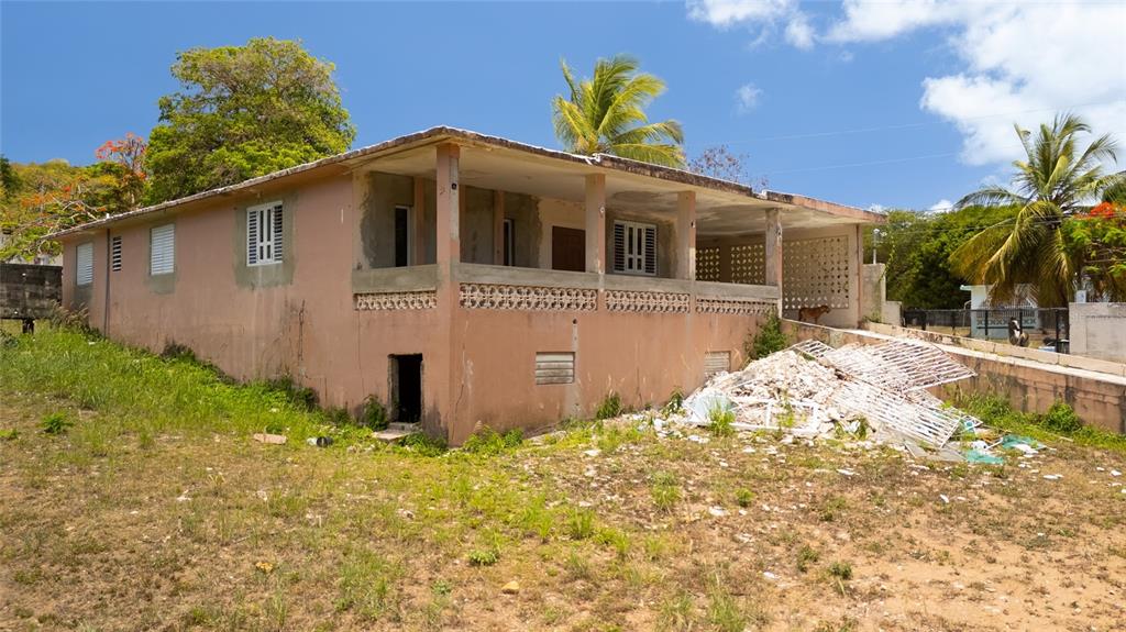 A single-story, peach-colored house with a porch and debris in the front yard — M-4 MONTE SANTO, VIEQUES, PR