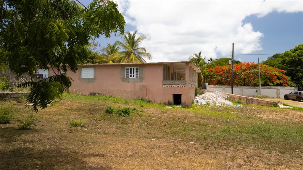 A pink, single-story house with a porch sits on a grassy lot with trees — M-4 MONTE SANTO, VIEQUES, PR