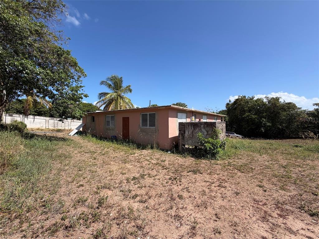 A single-story peach-colored house sits on a dry, grassy lot under a clear blue sky — M-4 MONTE SANTO, VIEQUES, PR