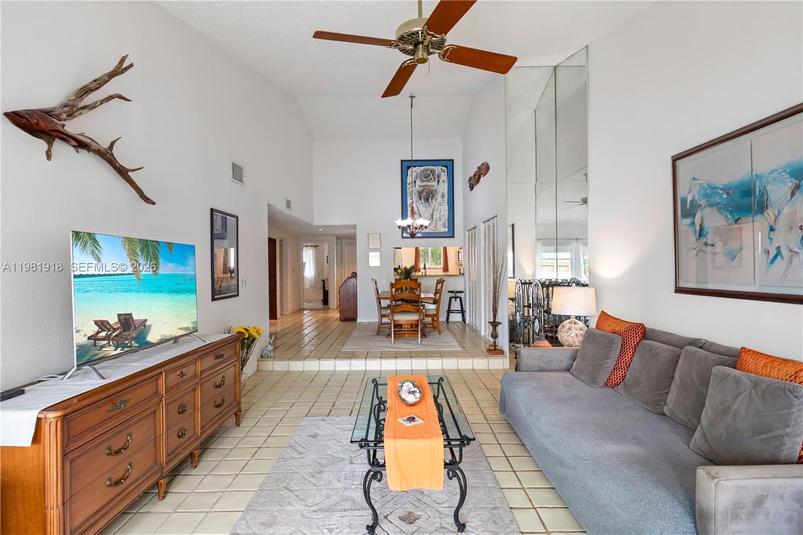 A living room with tile floors, a vaulted ceiling, a ceiling fan, and a dining area — 19994 NE 5th Ct # 3C, Miami FL 33179, MIAMI, FL