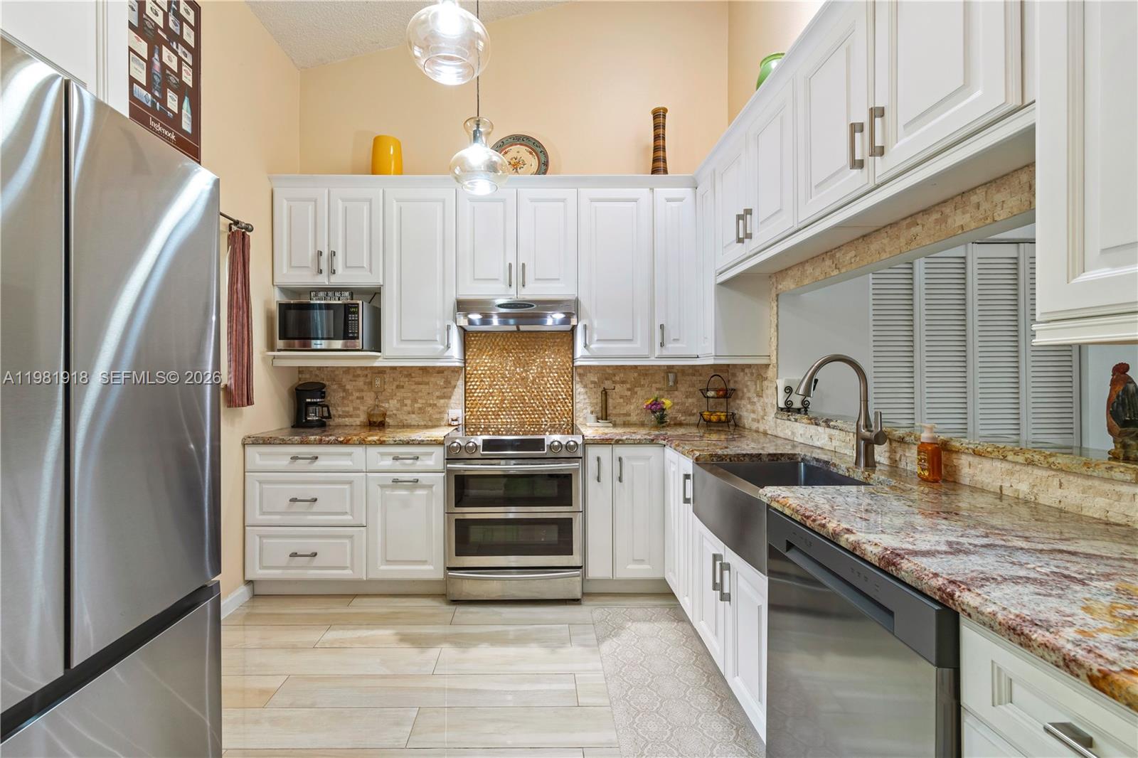 A kitchen features white cabinetry, stainless steel appliances, a farmhouse sink, and granite countertops — 19994 NE 5th Ct # 3C, Miami FL 33179, MIAMI, FL
