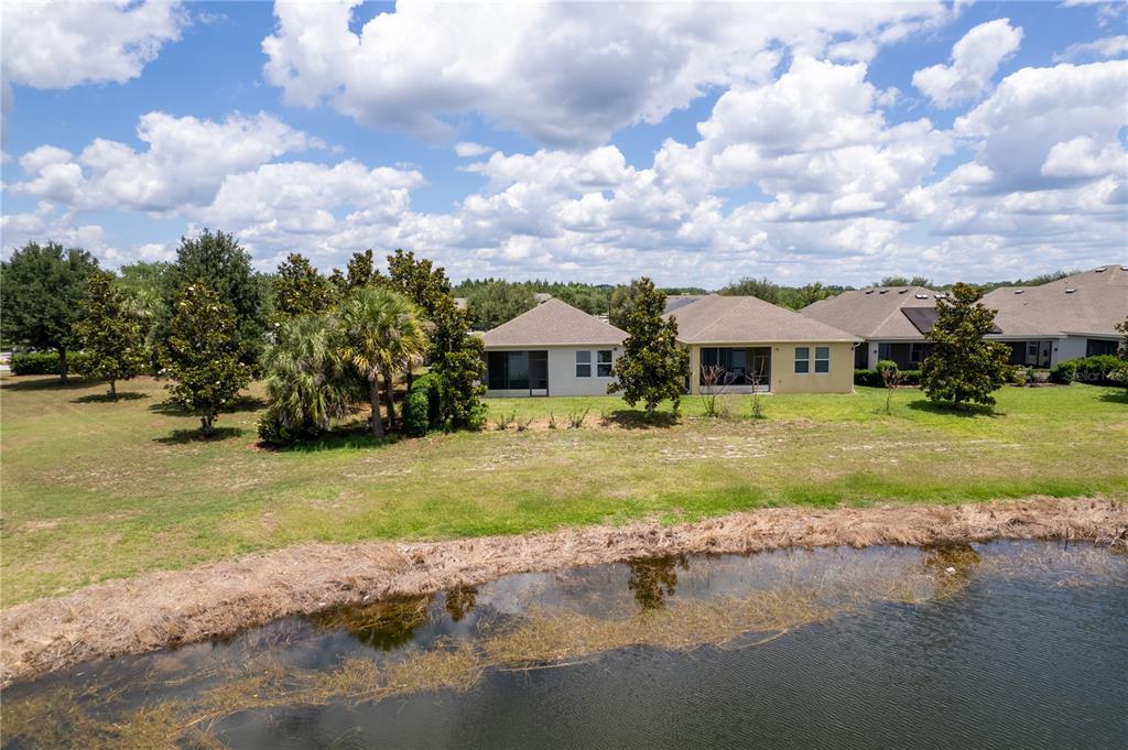 An aerial view shows the rear of two suburban houses overlooking a pond — 3300 SAGEBRUSH STREET, HARMONY, FL