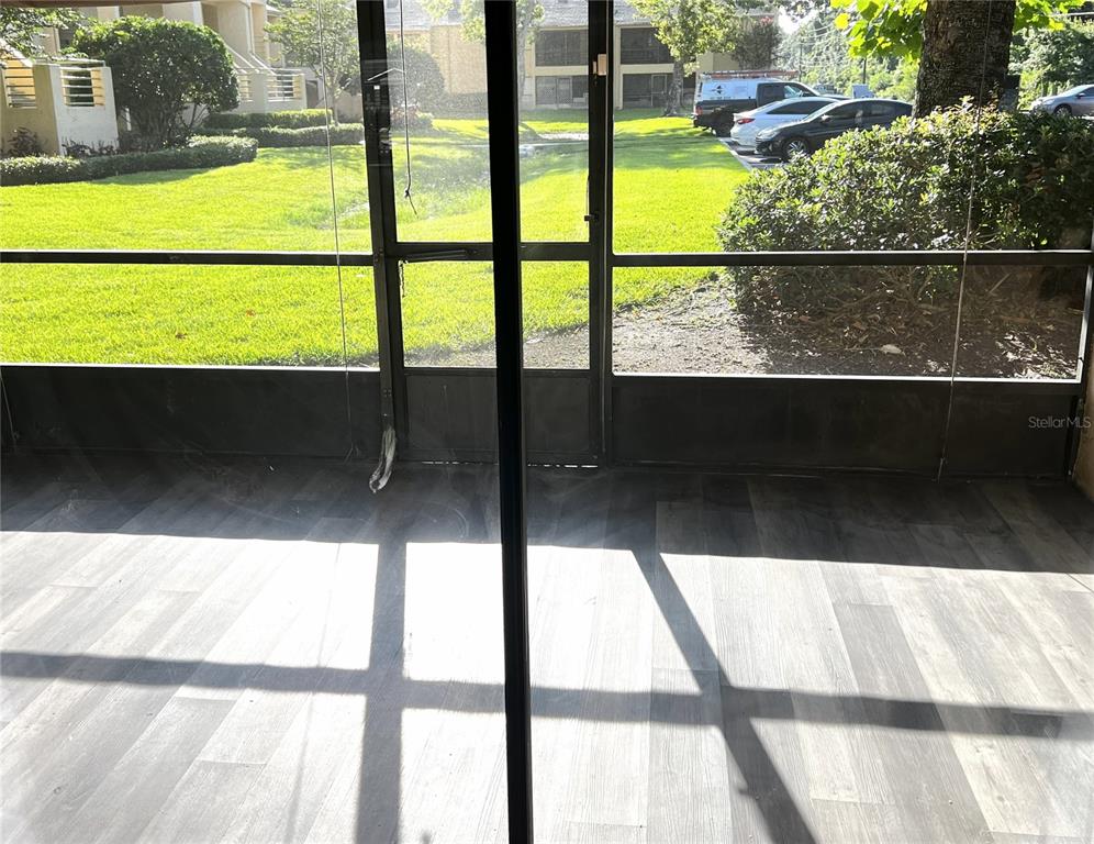 A view from a screened-in porch with wood-look flooring looking out toward a grassy lawn — 4440 S LAKE ORLANDO PARKWAY UNIT 6-4, ORLANDO, FL
