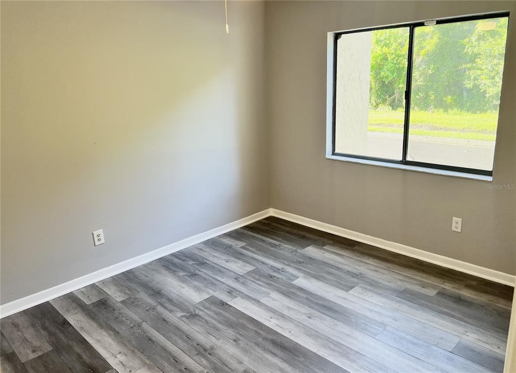 An empty room with gray walls, wood-look flooring, and a window overlooking a grassy area — 4440 S LAKE ORLANDO PARKWAY UNIT 6-4, ORLANDO, FL