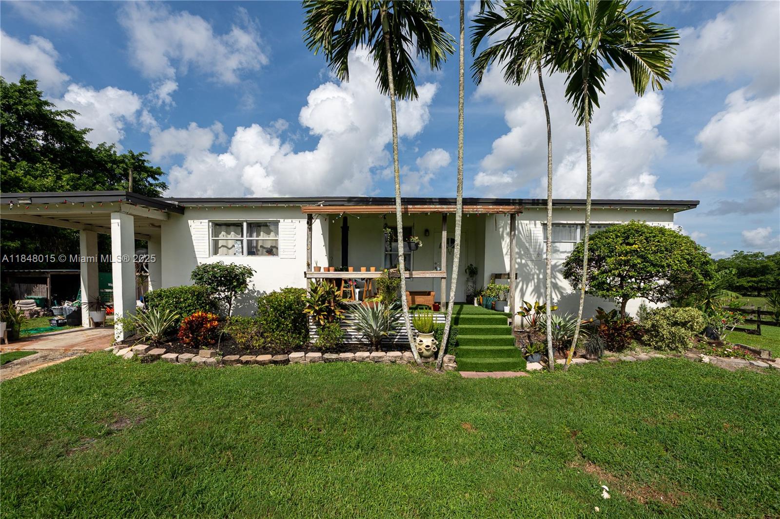 A single-story white house features a covered front porch, green steps, and tall palm trees — 1921 SW 112th Ave, Davie FL 33325, DAVIE, FL