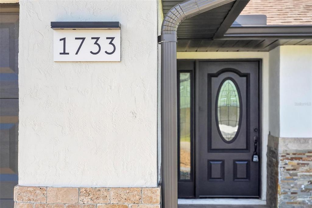 A single-story house with a stone-accented facade, a garage, and a green lawn — 1733 TWIN OAK STREET, DELTONA, FL