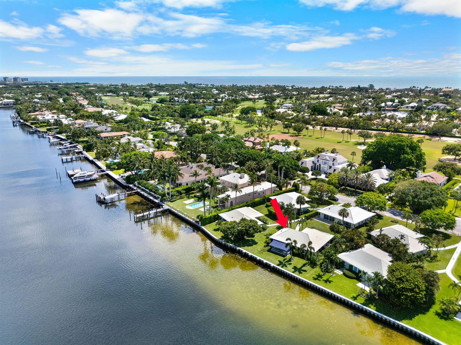 An aerial view shows a waterfront house with a red arrow pointing to its roof — 11639 Lost Tree Way # 22, North Palm Beach FL 33408, NORTH PALM BEACH, FL