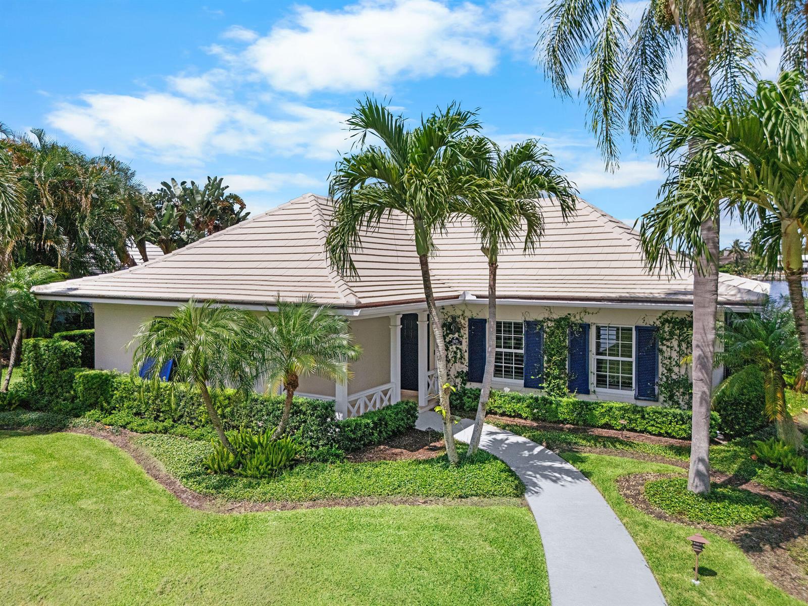 A single-story house with a beige roof, blue shutters, and palm trees in the yard — 11639 Lost Tree Way # 22, North Palm Beach FL 33408, NORTH PALM BEACH, FL
