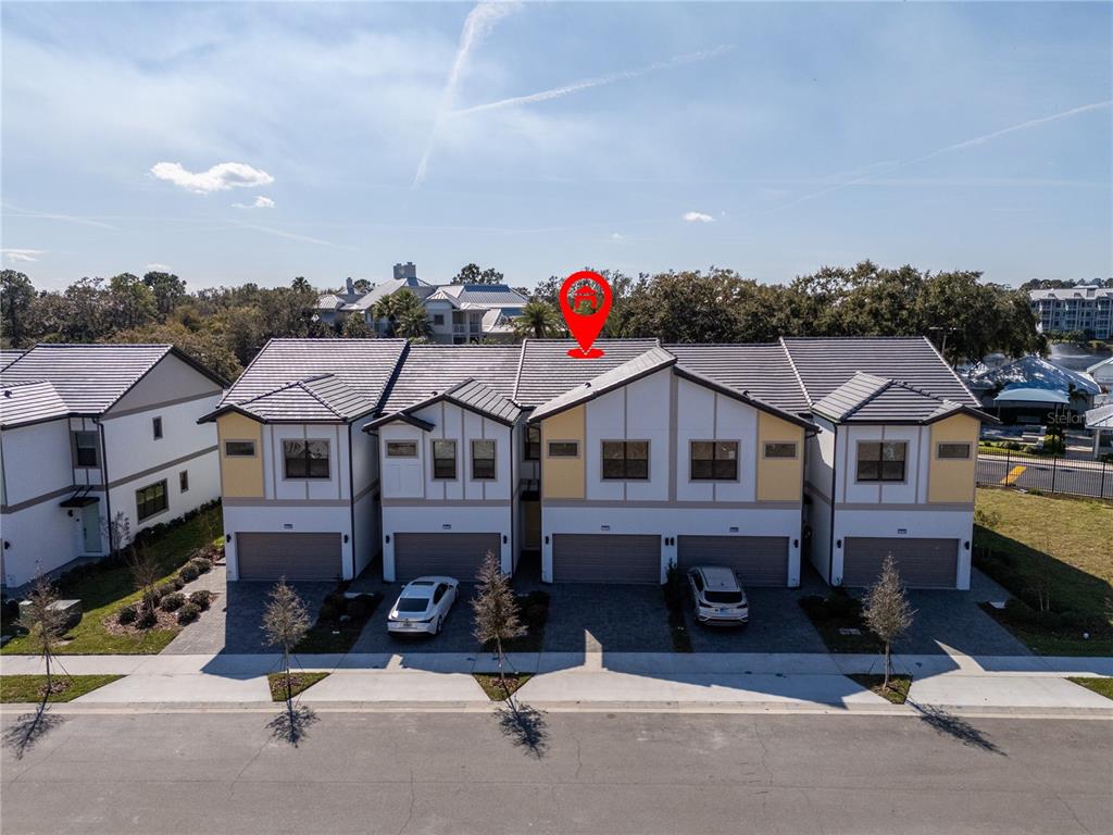 An exterior view of a multi-unit townhouse complex with a red location pin above — 10580 EBB TIDE LANE, ORLANDO, FL