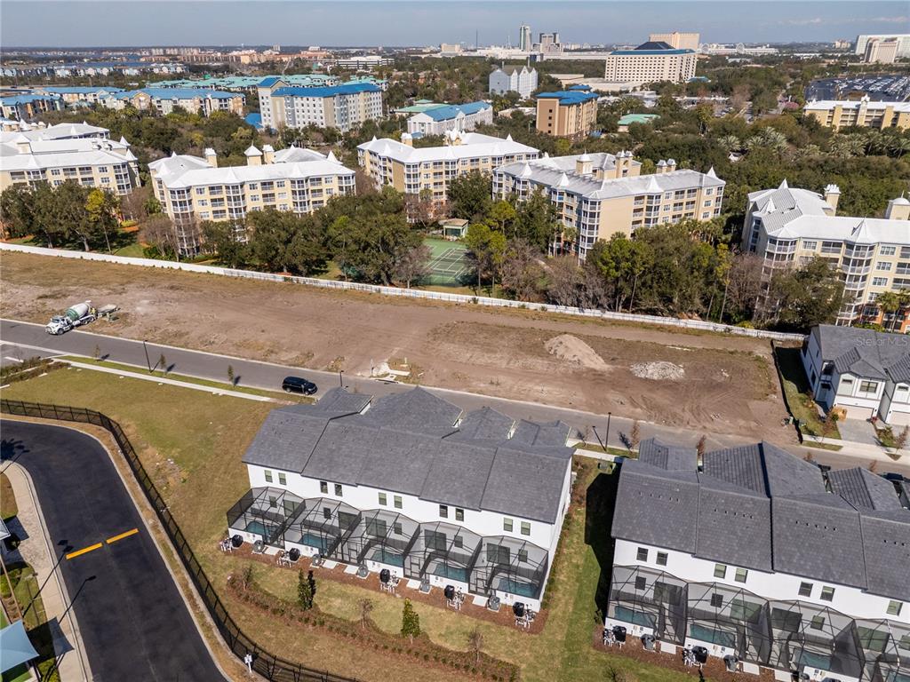 An aerial view shows townhomes with screened-in pools facing a vacant lot and apartment buildings — 10580 EBB TIDE LANE, ORLANDO, FL