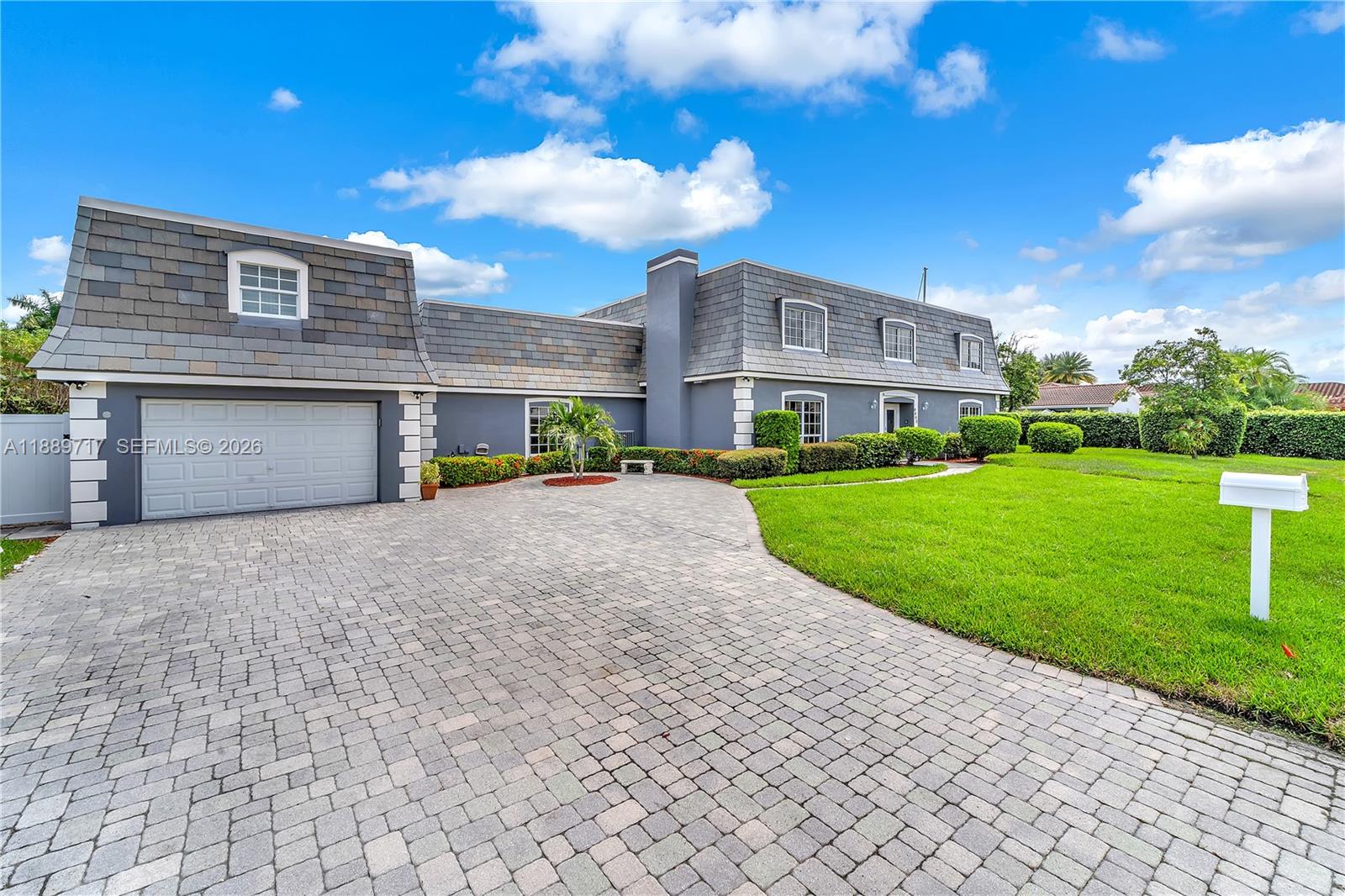 A gray two-story house with a mansard roof and a paved driveway sits on a lawn — 4440 NE 23rd Ave, Lighthouse Point FL 33064, LIGHTHOUSE POINT, FL