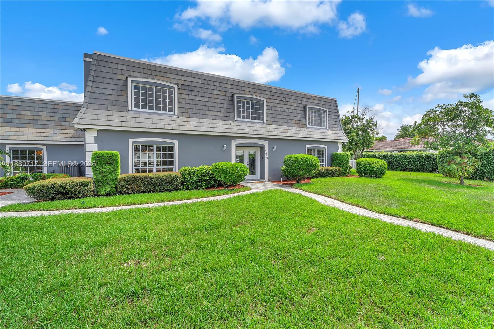 A two-story house with a gray mansard roof and a front lawn with walkways — 4440 NE 23rd Ave, Lighthouse Point FL 33064, LIGHTHOUSE POINT, FL