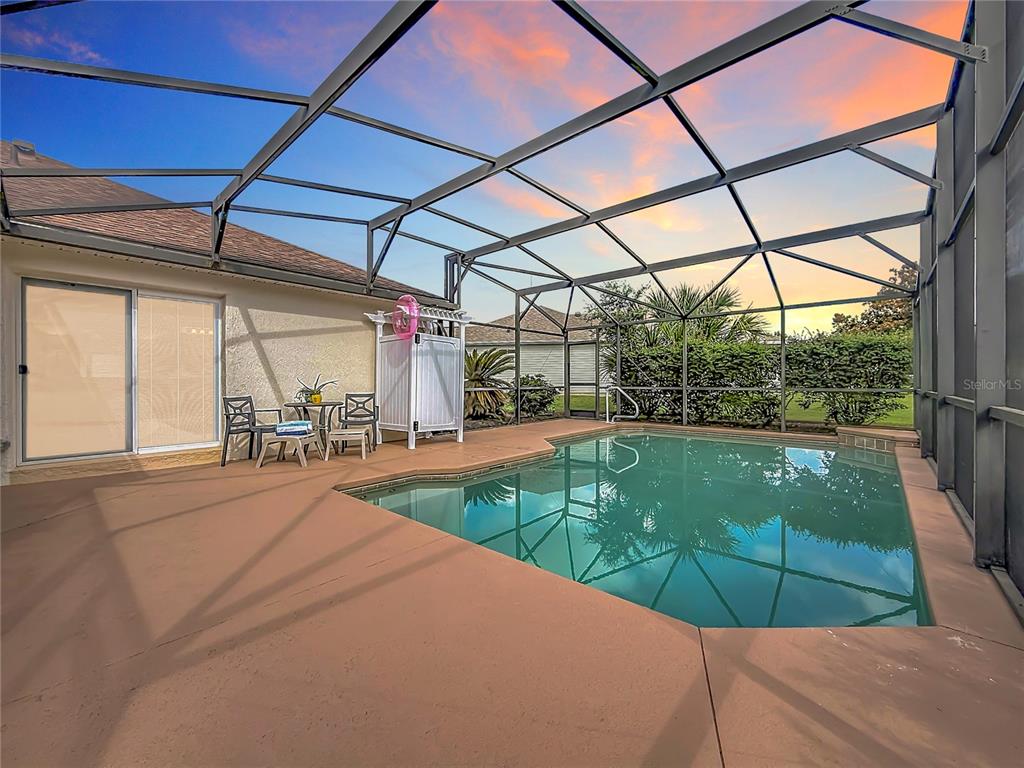 A screened-in pool patio features a small dining set and a white privacy screen — 8641 SE 168TH KITTREDGE LOOP, THE VILLAGES, FL