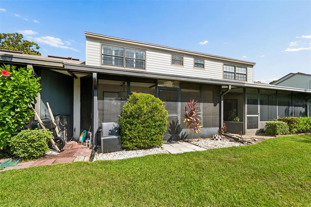 The exterior of a two-story house features a screened-in patio and a grassy backyard — 612 QUAIL KEEP DRIVE, SAFETY HARBOR, FL