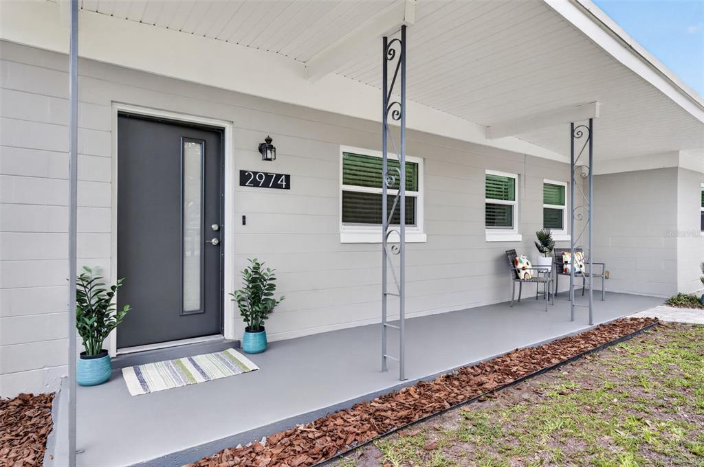 A gray house exterior features a covered porch, a modern front door, and metal columns — 2974 CHANTILLY AVENUE, WINTER PARK, FL