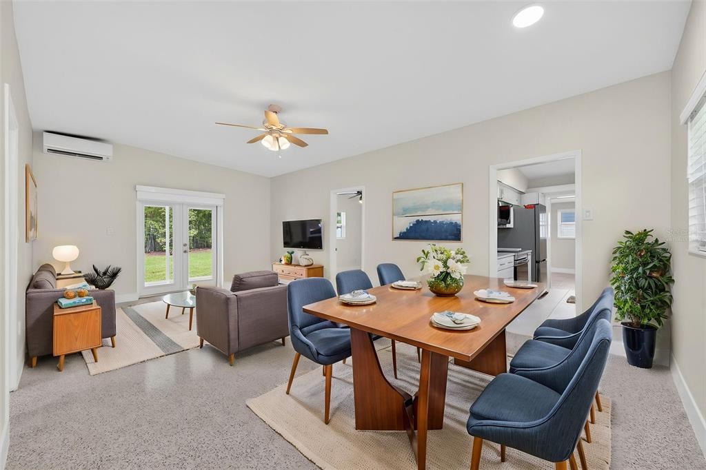 A dining area and living room with a wooden table, blue chairs, and glass doors — 2974 CHANTILLY AVENUE, WINTER PARK, FL