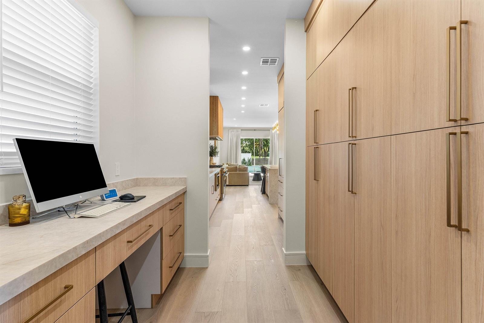 A home office nook with light wood cabinetry leads into a kitchen and living area — 9701 Spray Drive, West Palm Beach FL 33411, WEST PALM BEACH, FL