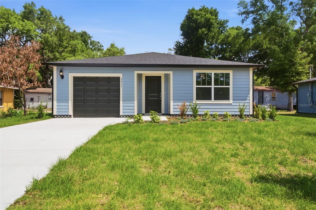 A light blue single-story house features a dark garage door, front door, and roof — 3411 WARREN SAPP DRIVE, APOPKA, FL