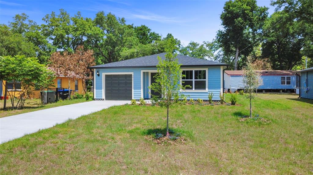 A light blue single-story house with a dark gray garage door and a concrete driveway — 3411 WARREN SAPP DRIVE, APOPKA, FL