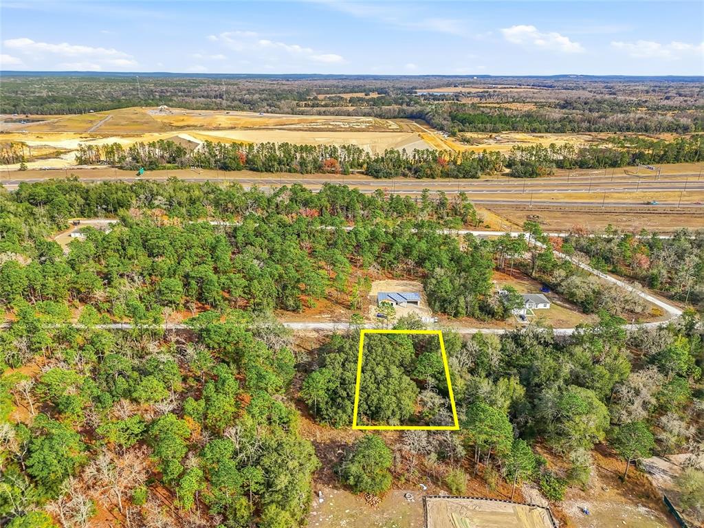 An aerial view shows a wooded lot outlined in yellow near a road and highway — CAYMAN ROAD, WEEKI WACHEE, FL
