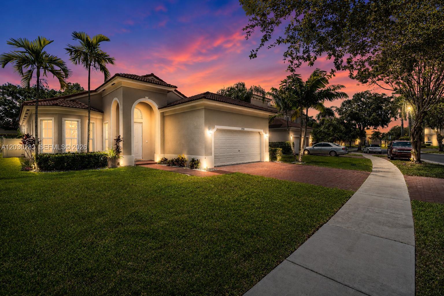 A single-story house with a brick driveway, palm trees, and a sunset sky — 1785 NE 37th Pl, Homestead FL 33033, HOMESTEAD, FL