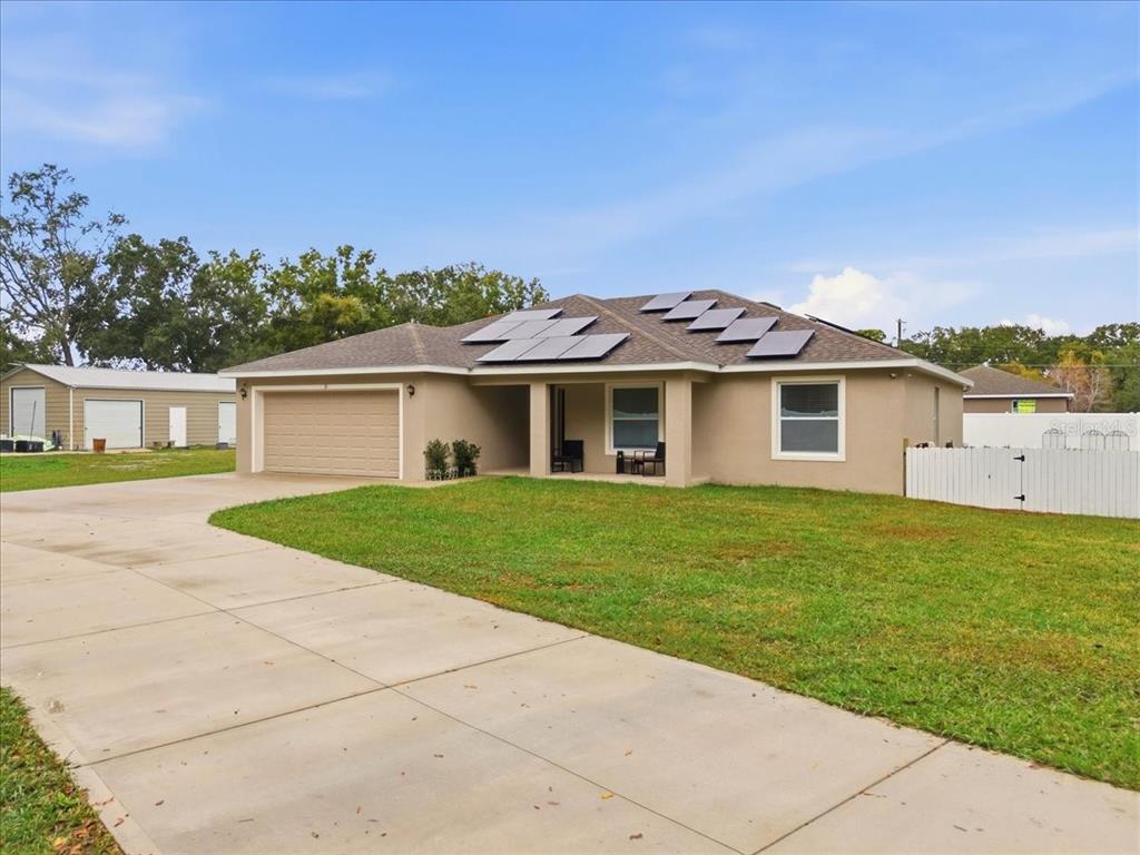 A single-story tan house with a concrete driveway, solar panels, and a detached garage — 31 MORGAN STREET, AUBURNDALE, FL
