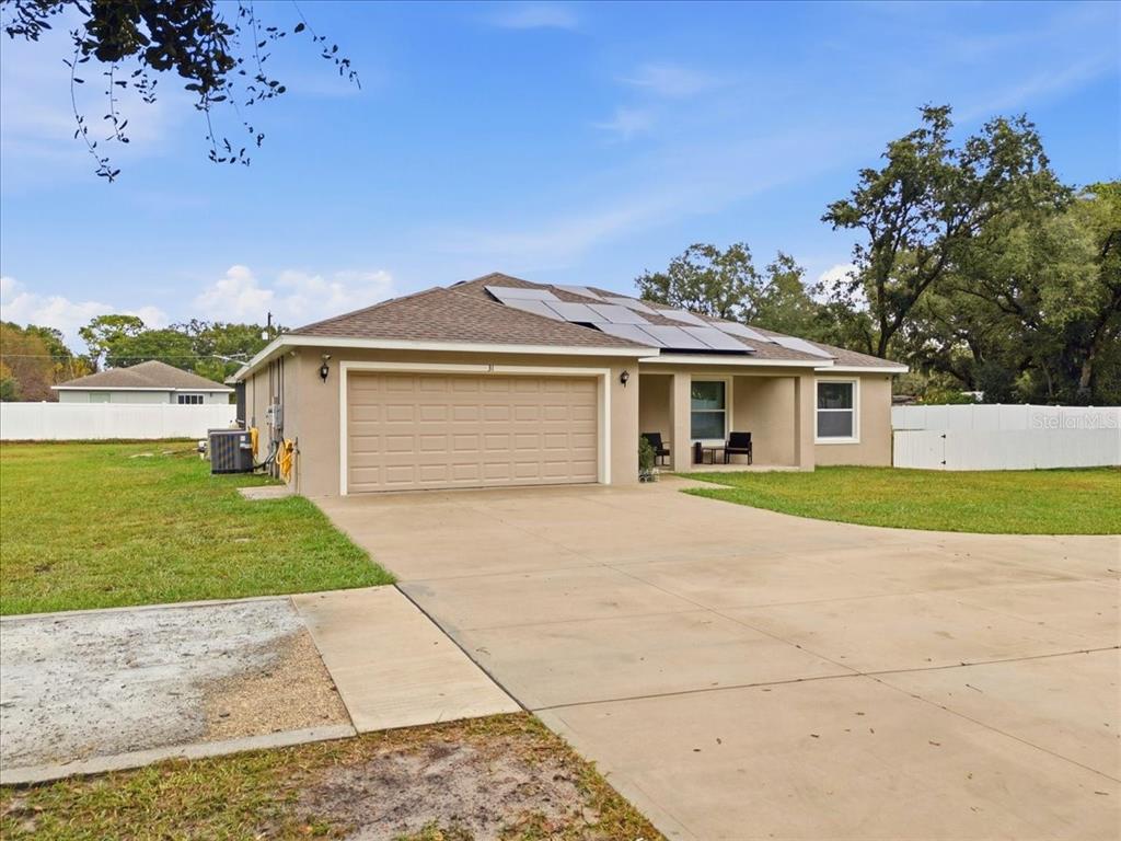 A single-story house with a two-car garage and solar panels on the roof — 31 MORGAN STREET, AUBURNDALE, FL