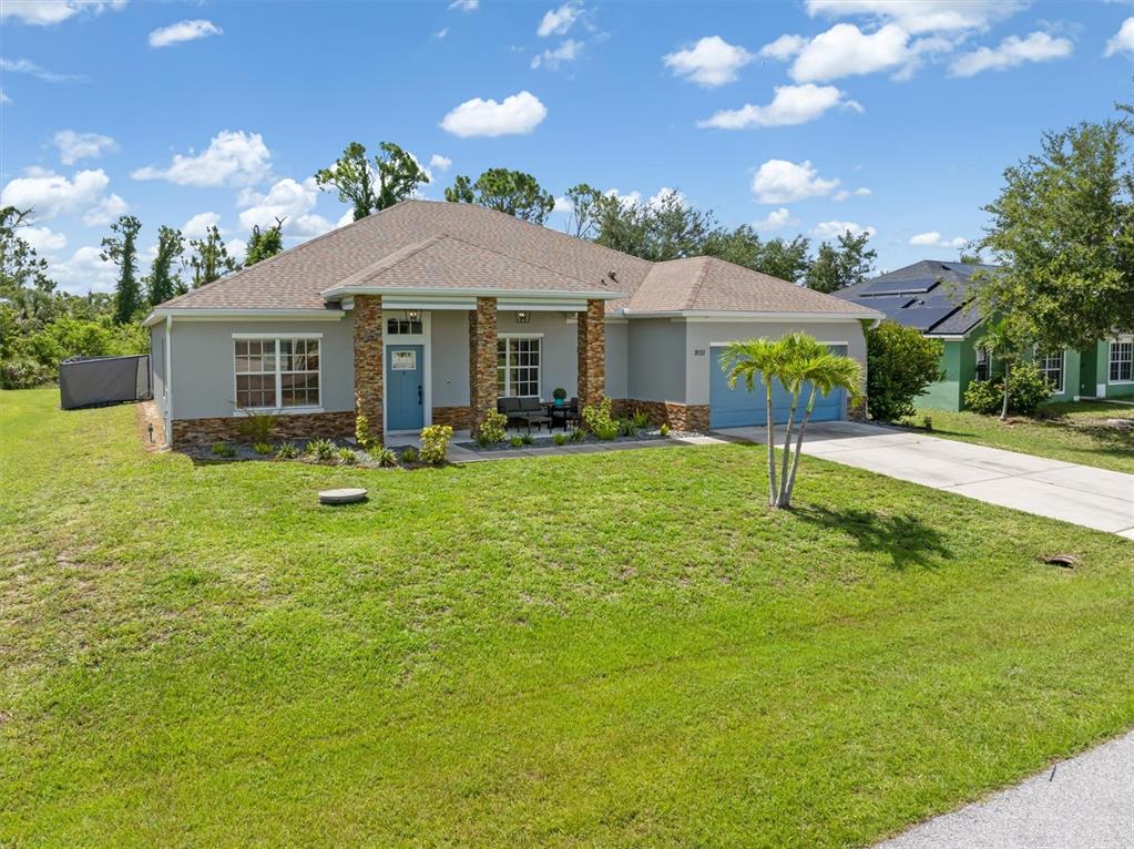 A single-story suburban house with a stone-accented porch, blue front door, and attached garage — 9151 MELODY CIRCLE, PORT CHARLOTTE, FL