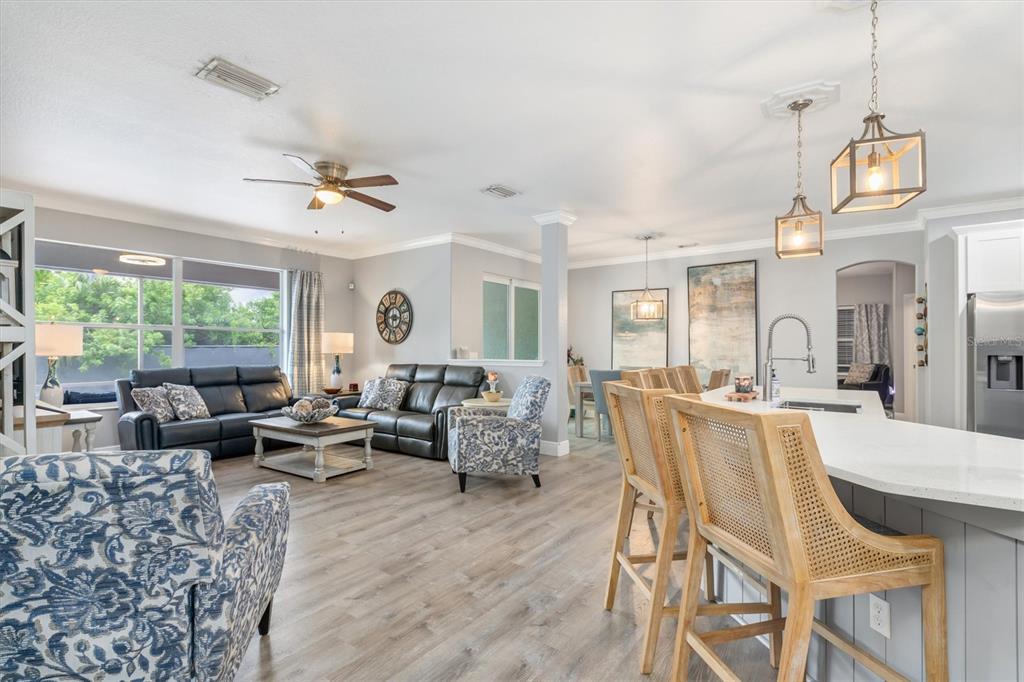 An open-concept living room and kitchen feature gray walls, wood-look flooring, and blue patterned furniture — 9151 MELODY CIRCLE, PORT CHARLOTTE, FL