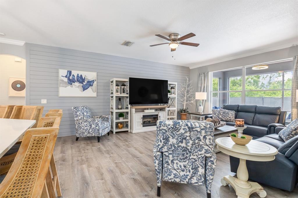 A living room features a shiplap accent wall, a television, and blue patterned armchairs — 9151 MELODY CIRCLE, PORT CHARLOTTE, FL