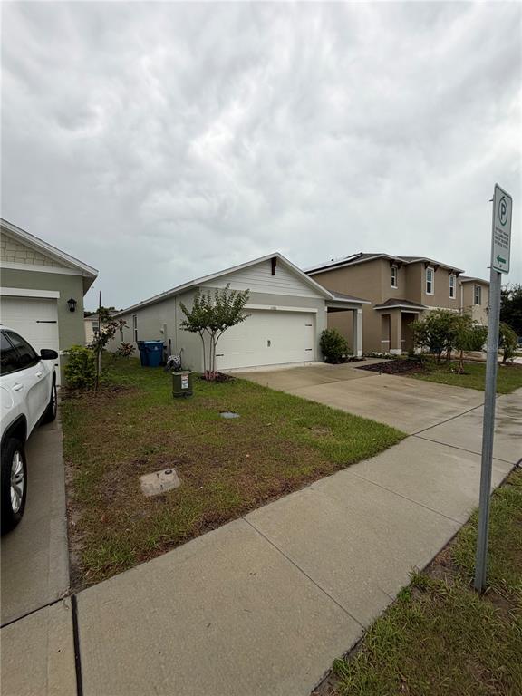 A single-story house with a two-car garage and a concrete driveway under a cloudy sky — 1360 BERRY LANE, DAVENPORT, FL