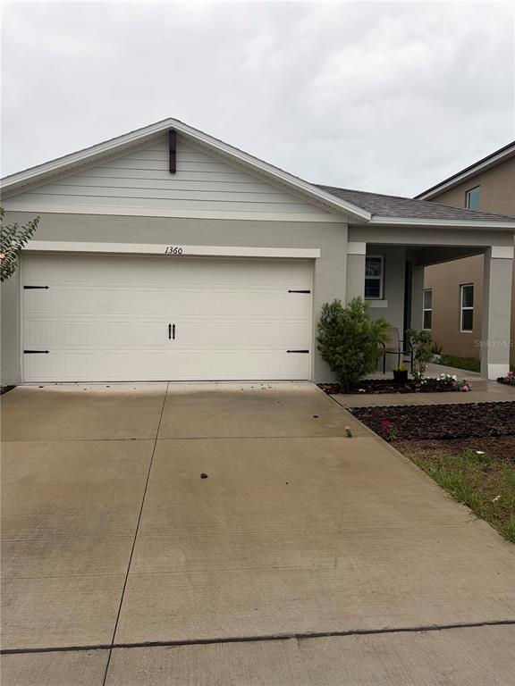 A single-story house with a white garage door, concrete driveway, and a covered front porch — 1360 BERRY LANE, DAVENPORT, FL