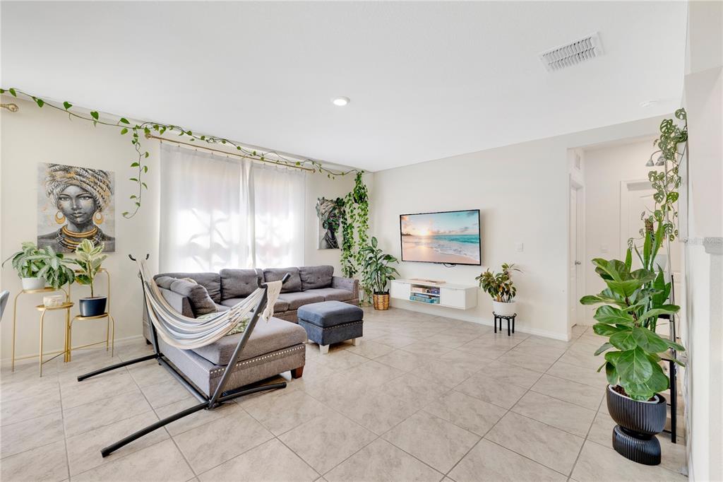 A living room features a gray sectional sofa, a hammock, tile flooring, and several houseplants — 831 TURNER LANE, WINTER HAVEN, FL