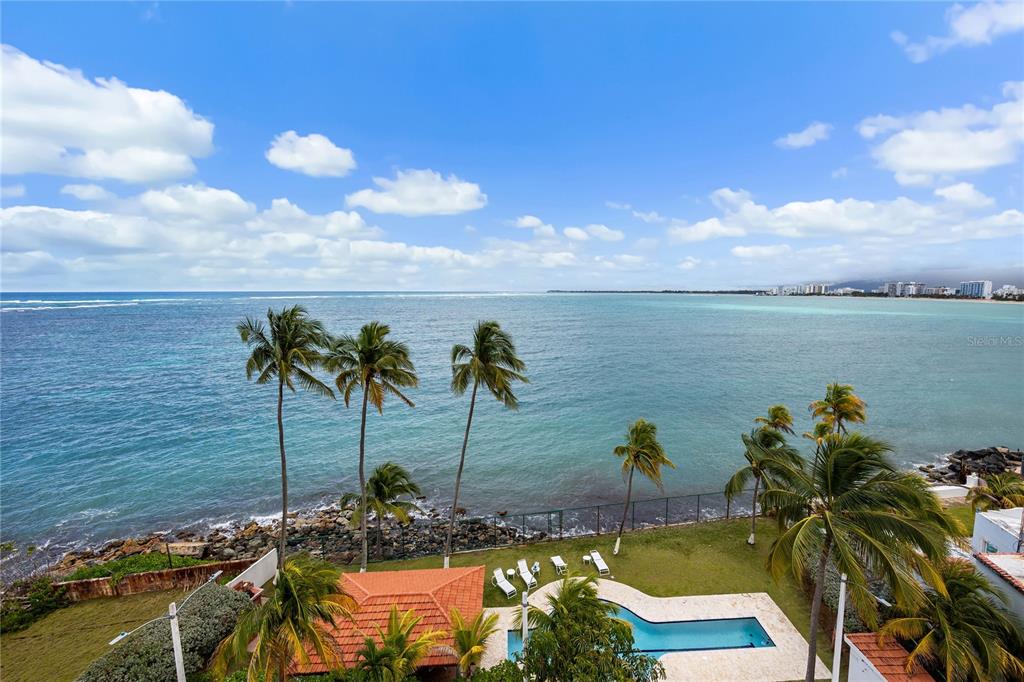 An elevated view of a swimming pool, palm trees, and a rocky coastline overlooking the ocean — 9 EMAJAGUA UNIT 7B, SAN JUAN, PR