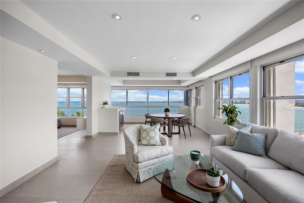 A bright living and dining area features tile floors, neutral furniture, and expansive ocean views — 9 EMAJAGUA UNIT 7B, SAN JUAN, PR