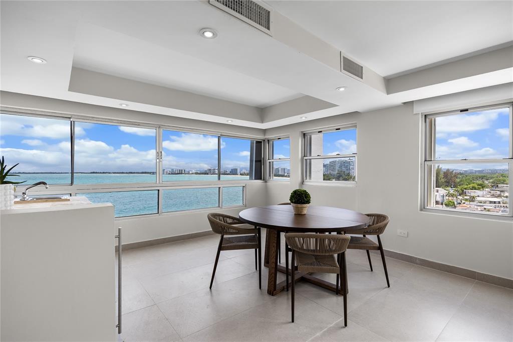 A dining area with a round wooden table, woven chairs, and panoramic ocean views — 9 EMAJAGUA UNIT 7B, SAN JUAN, PR