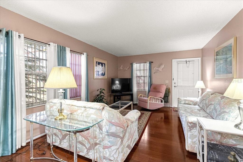 A living room features floral sofas, a glass coffee table, and hardwood floors — 7885 MIDWAY DRIVE TERRACE UNIT E101, OCALA, FL