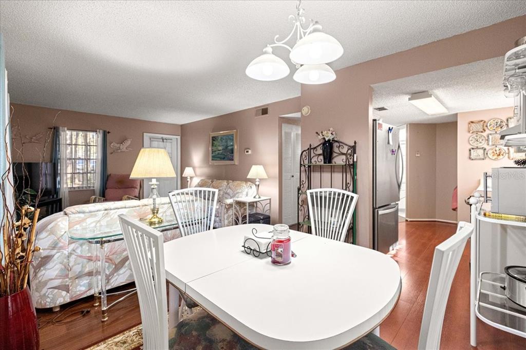A dining area with a white table and chairs opens into a living room space — 7885 MIDWAY DRIVE TERRACE UNIT E101, OCALA, FL