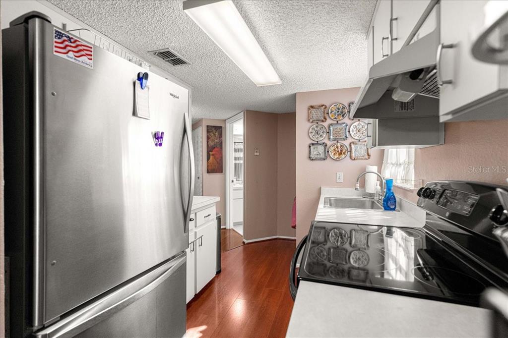 A kitchen features stainless steel appliances, white cabinets, a light countertop, and wood-look flooring — 7885 MIDWAY DRIVE TERRACE UNIT E101, OCALA, FL