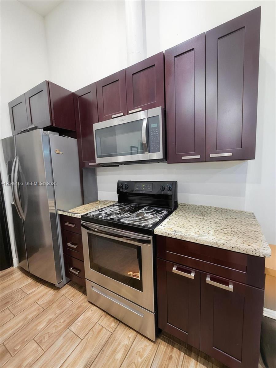 An empty room features light wood-look tile flooring, white walls, and a sliding glass door — 2566 N Nob Hill Rd, Sunrise FL 33322, SUNRISE, FL