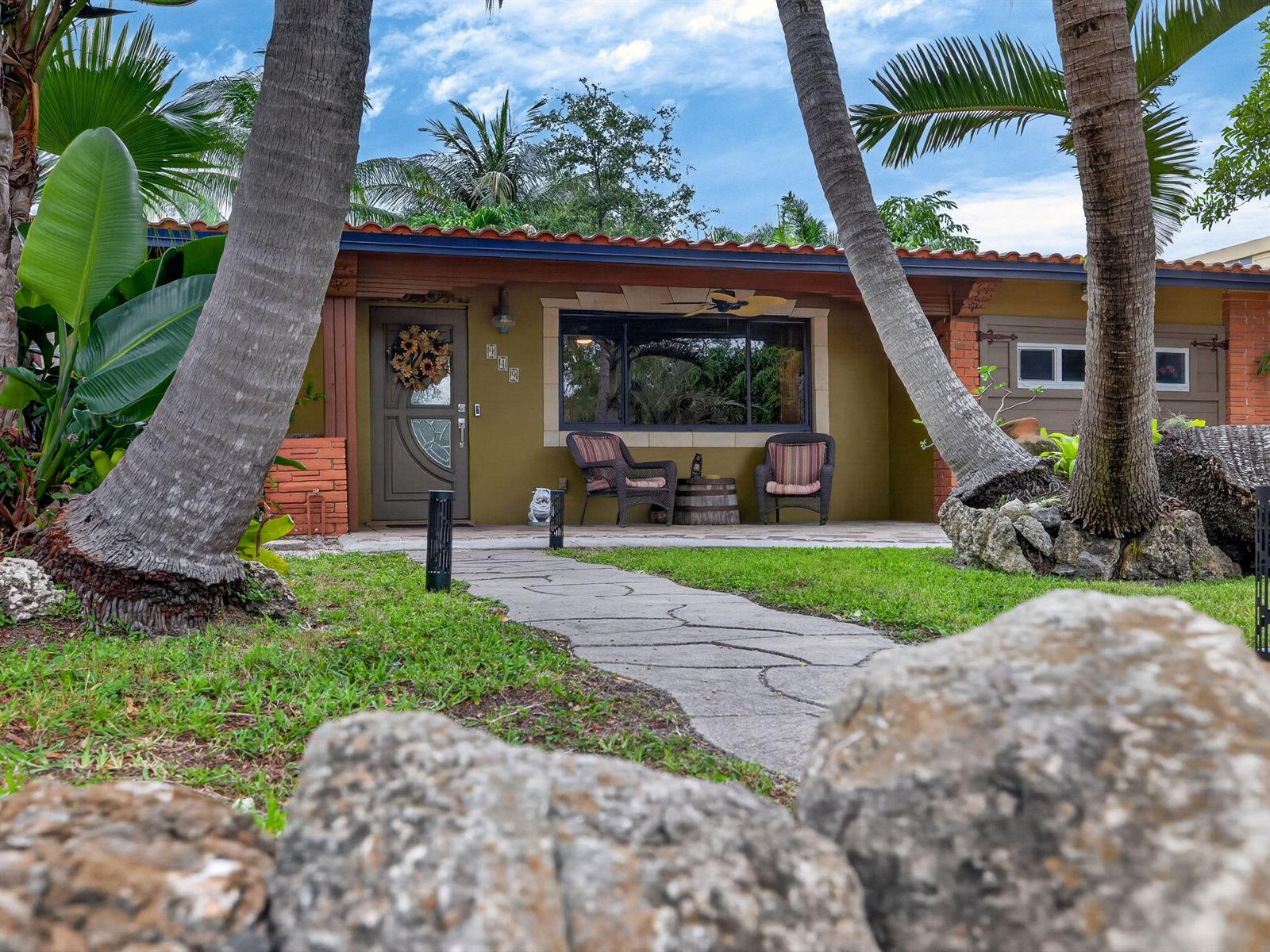 A single-story house with a brown exterior, tiled roof, and a stone walkway leading to the entrance — 949 NE 25th Avenue, Pompano Beach FL 33062, POMPANO BEACH, FL