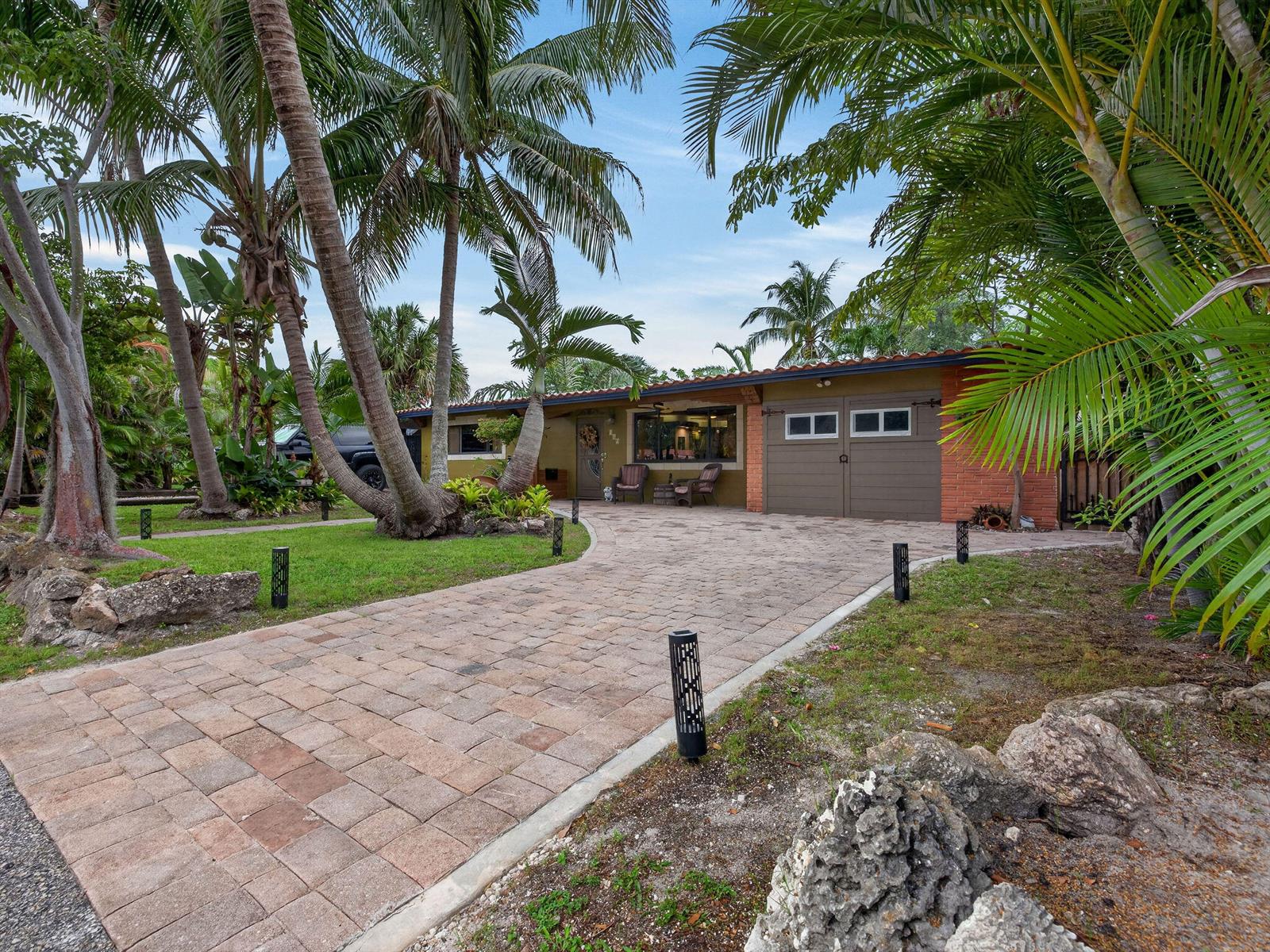 A single-story house with a brick facade, a paved driveway, and palm trees in front — 949 NE 25th Avenue, Pompano Beach FL 33062, POMPANO BEACH, FL