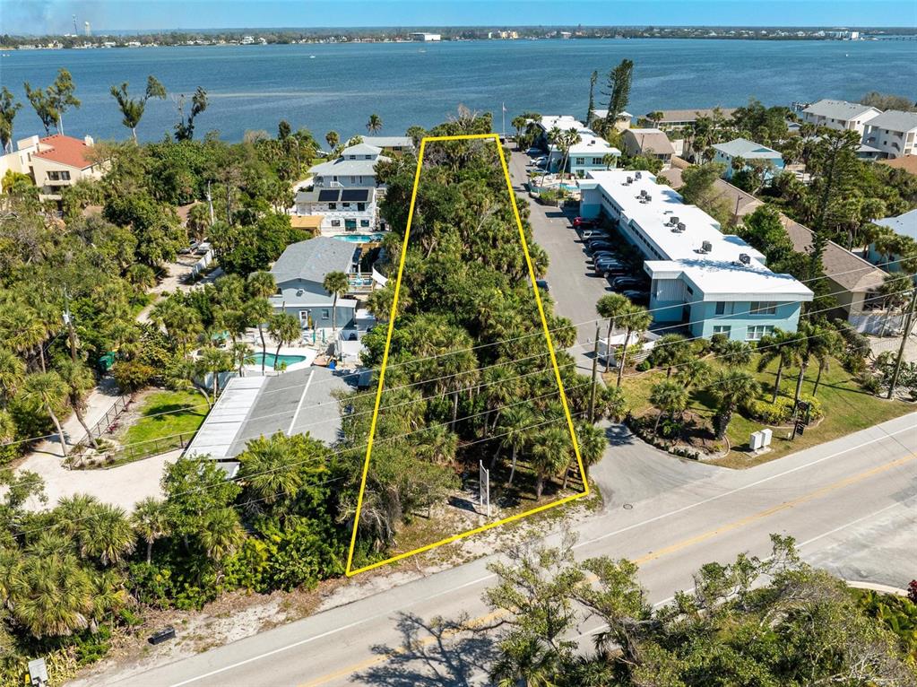 An aerial view shows a vacant, tree-covered lot outlined in yellow next to a road — 5065 N BEACH ROAD, ENGLEWOOD, FL